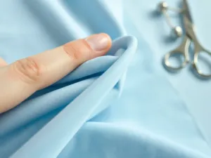 Kobieta wyjmuje czystą, puszystą kurtkę puchową z nowoczesnej pralki w jasnej, uporządkowanej pralni.